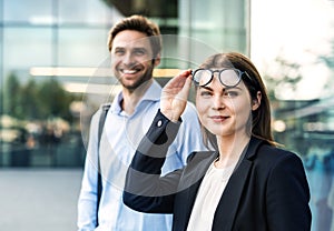 A portrait of young businessman and businesswoman standing outdoors.