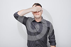 Portrait of young businessman covering eyes with hand isolated on white studio