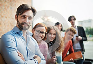 Portrait of young businessman with group of entrepreneurs indoors in office, looking at camera.
