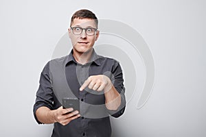 Portrait of young businessman with mobile phone in hand celebrates victory, winning money in casino. Person with smartphone