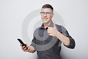 Portrait of young businessman with mobile phone in hand celebrates victory, winning money in casino. Person with smartphone