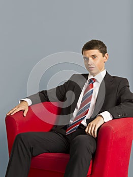 Portrait of young businessman sitting in armchair