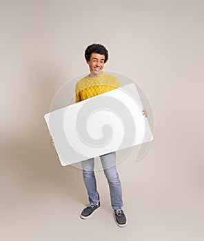 Portrait of young businessman smiling and presenting blank poster while standing on white background