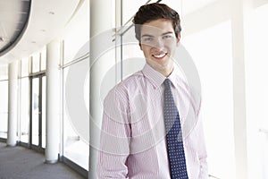 Portrait Of Young Businessman Standing In Corridor Of Modern Off