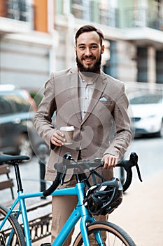 Portrait of a young businessman in a suit with a bicycle. The ecological path to work