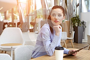 portrait of young businesswoman looking at touch pad screen whil