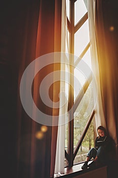 Portrait of young businesswoman with notebook and phone at window