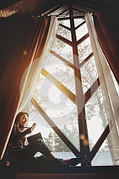 Portrait of young businesswoman with notebook and phone at window