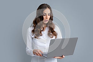 Portrait of young businesswoman using laptop computer isolated on gray background. Business women in shirt excited