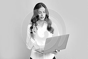 Portrait of young businesswoman using laptop computer isolated on gray background. Business women in shirt excited