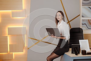 Portrait of a young businesswoman working on a laptop in an modern office