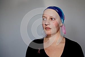 Portrait of a young cancer patient in a headscarf looks off to side