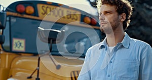 Portrait car driver stand near yellow school bus. Serious man looking camera.