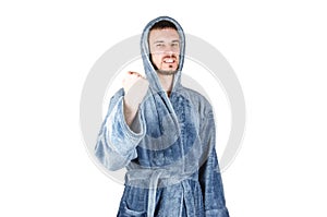 Portrait of young caucasian bearded man in blue bathrobe raises fist isolated on white background