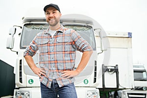 Portrait of young Caucasian bearded trucker standing by his truck vehicle. Transportation service. Truck driver job.