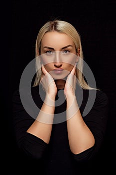 Portrait of a young Caucasian beautiful blonde woman. her hands on her face