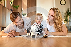 Portrait of young caucasian family having fun with dog at home