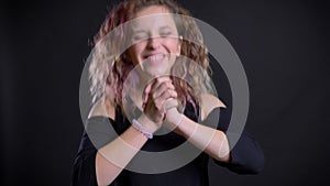 Portrait of young caucasian girl with pink hair jumping in great happiness on black background.