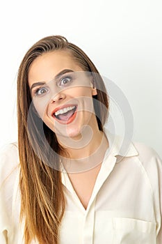 Portrait of a young caucasian happy woman wearing white shirt smiling with open mouth against the white background.