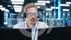 Portrait of a Young Caucasian Male Call Centre Worker Wearing a Phone Headset Talking at the Suppo