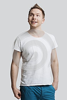 Young Caucasian man in casuals looking away against white background photo
