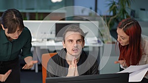 Portrait of young Caucasian man making effort calming down as women gesturing shouting examining paperwork in office