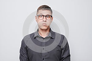 Portrait of young caucasian man puffing cheeks with funny face isolated on white studio background. Humor concept