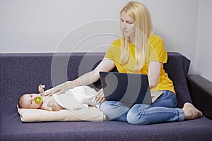 Portrait of Young Caucasian Mother WIth Baby Boy Remote Working Using Laptop