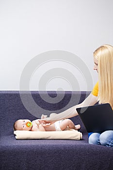 Portrait of Young Caucasian Mother WIth Baby Boy Remote Working Using Laptop