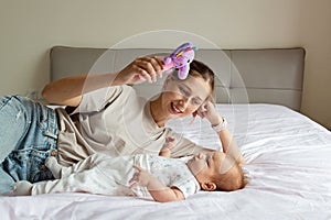 Portrait of young Caucasian mother holds hug little toddler baby two months old, relax together in sofa at home, happy