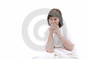 Portrait of young caucasian woman in bed with glass of water. Habit of drinking water in the morning. Copy space. White background