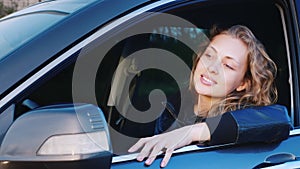 Portrait of a young caucasian woman in a car. Sitting in the driver`s seat, looking at the camera, smiling
