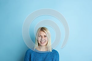 Portrait of young caucasian woman looks happy, dreamful on blue background