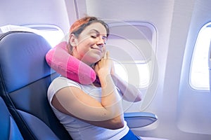 Portrait of a young caucasian woman on a plane with a travel pillow around her neck