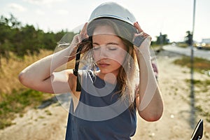 Portrait of young caucasian woman putting on helmet