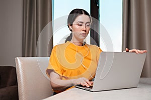 Portrait of a young caucasian woman sitting at a desk with headphones on, and studying online on a laptop. The concept