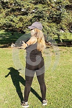 Portrait of a young Caucasian woman in sportswear doing waist rotations in a park. Concept of outdoor pursuit in springtime and
