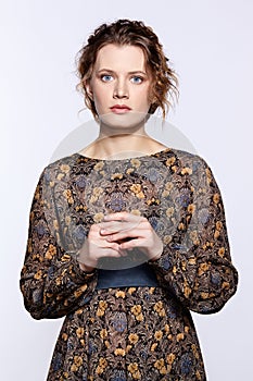 Portrait of a young caucasian woman in vintage retro dress and wavy hair on a gray background