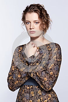 Portrait of a young caucasian woman in vintage retro dress and wavy hair on a gray background