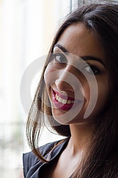 Portrait of a young charming girl sitting near a window