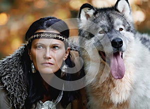 Portrait of a young charming woman with an Alaskan Malamute dog in the forest