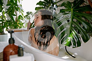 Portrait of young charming woman relaxing in bathtub enjoying organic skincare