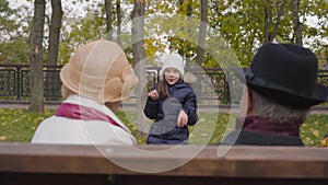 Portrait of a young cheerful Caucasian girl in white hat jumping like a rabbit in front of her grandparents. Happy