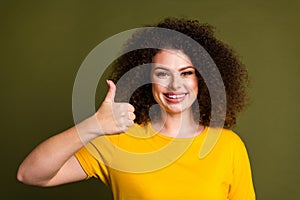 Portrait of young cheerful lady wearing yellow t shirt showing thumb up like symbol mcdonalds food isolated on khaki