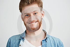 Portrait of young cheerful merry guy making funny face fooling looking at camera over white background.