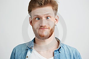 Portrait of young cheerful merry guy making funny face fooling looking at camera over white background.