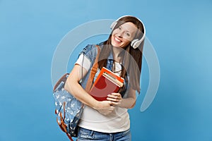 Portrait of young cheerful pleasant woman student in denim clothes with backpack headphones listening music, hold school