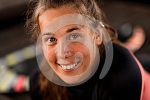 Portrait of young cheerful woman with brown color eyes in black wetsuit.