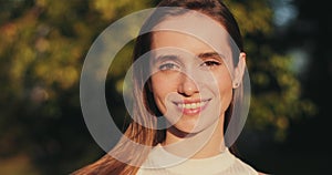 Portrait of young cheerful woman posing while standing outdoors. Close up view of millennial brunnette girl with