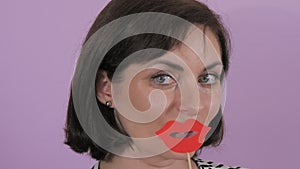 Portrait of a young cheerful woman putting on a carnival paper mask of red lips slow motion